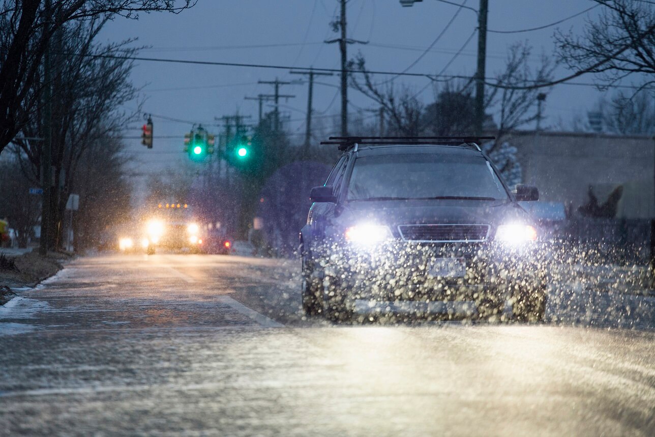 Car driving on snowy urban street at night