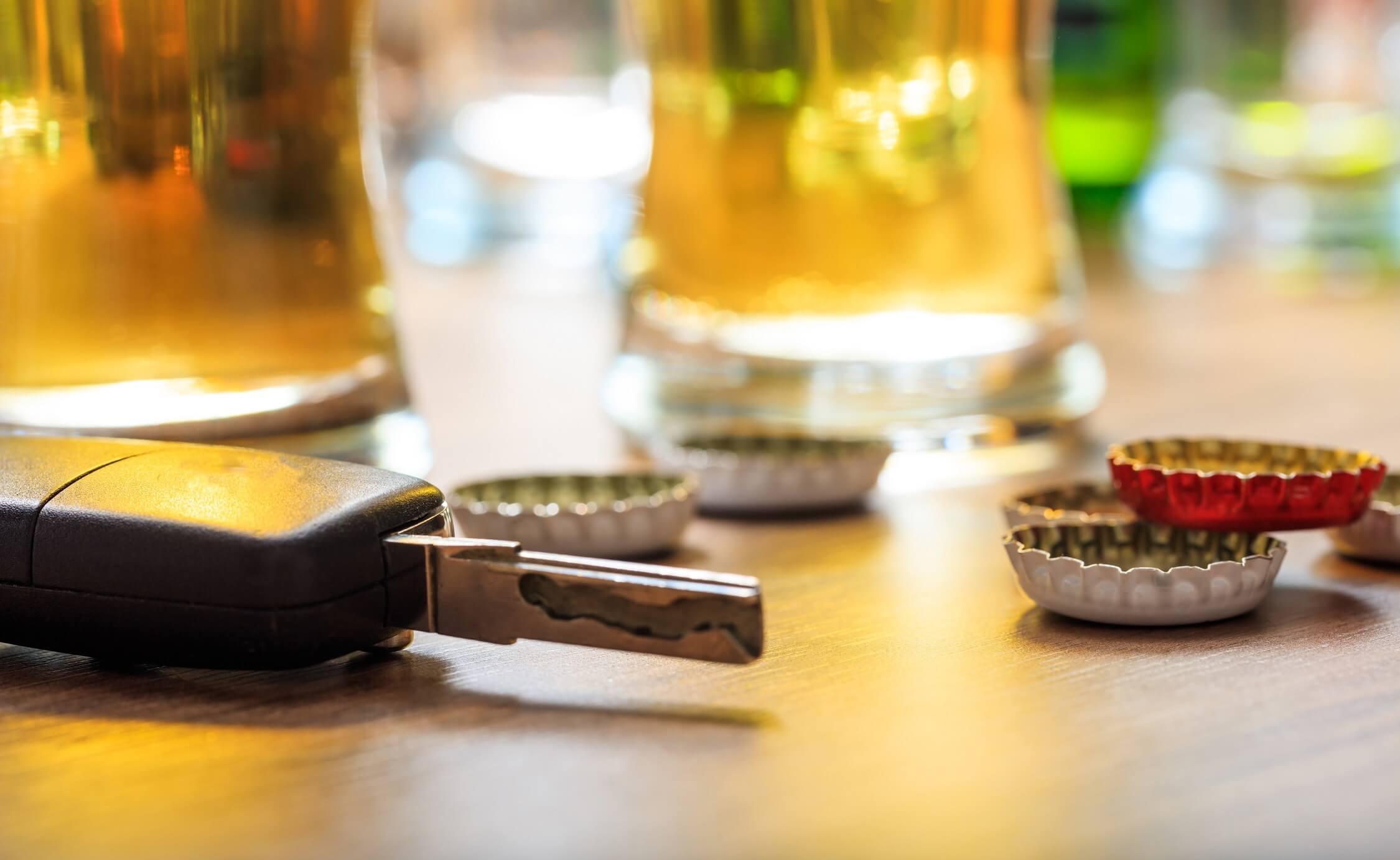 Drinking and driving concept. Car key on a wooden table, pub background