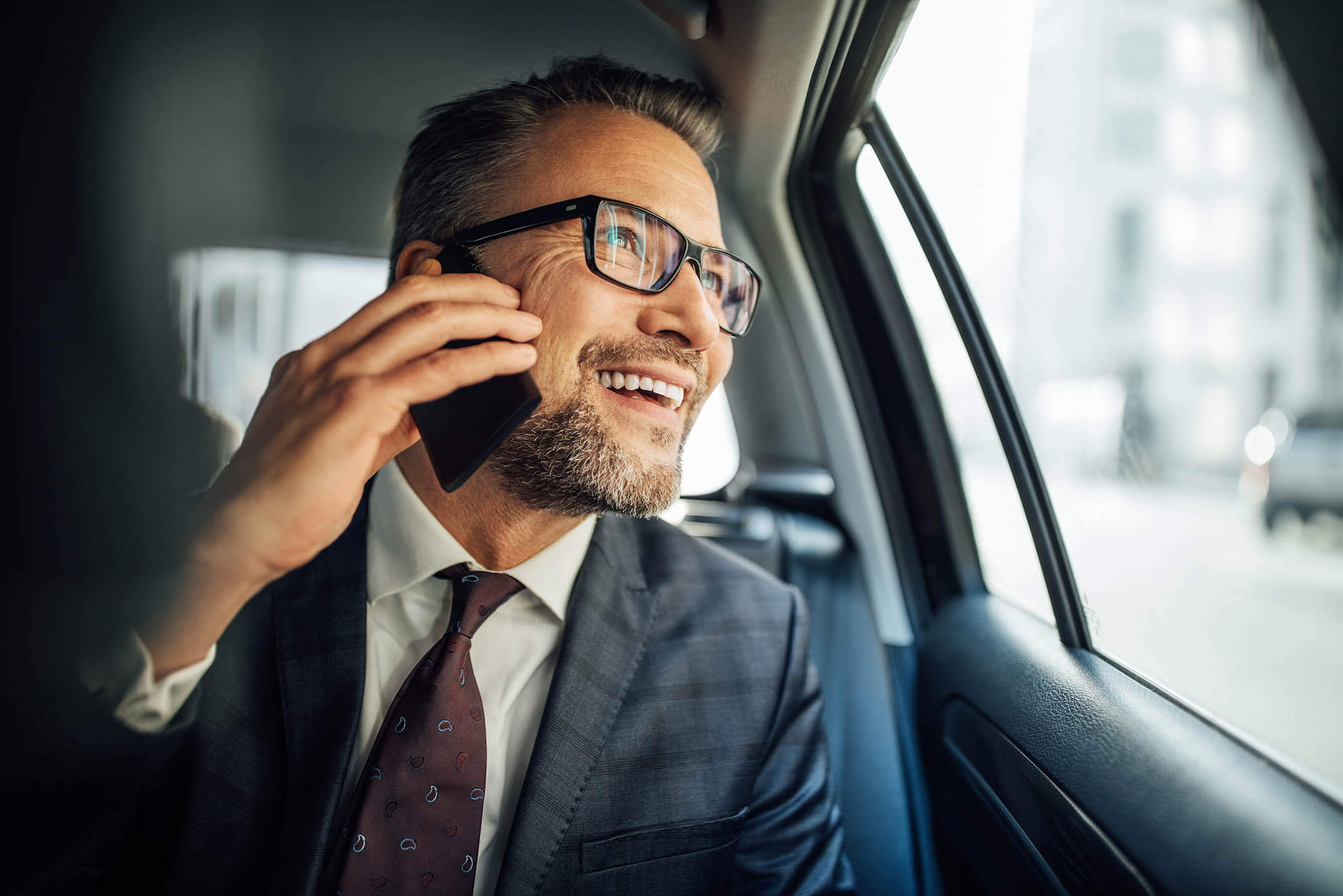 Smiling businessman on cell phone in a taxicab